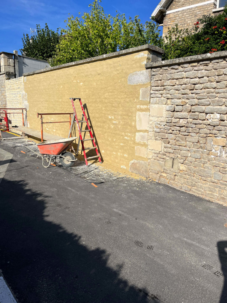 Mur en rénovation avec échafaudage et brouette, extérieur