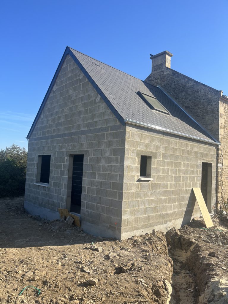 Maison en construction avec toit en ardoise.